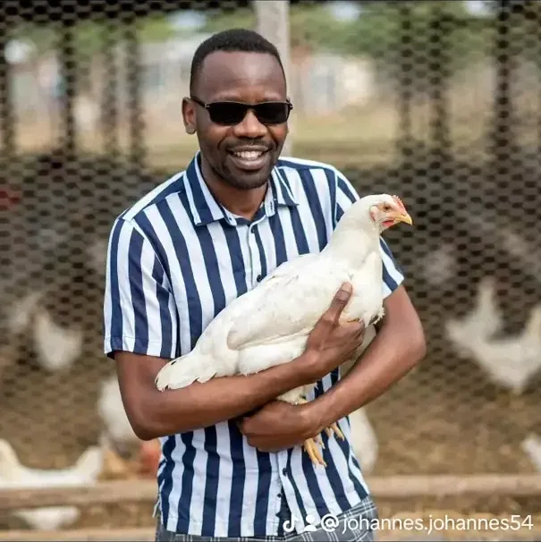 A man holding a white chicken at the poultry farm